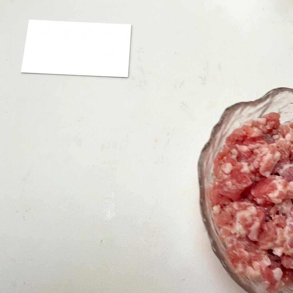 ガラスボウルに入ったひき肉に調味料を加えている様子。