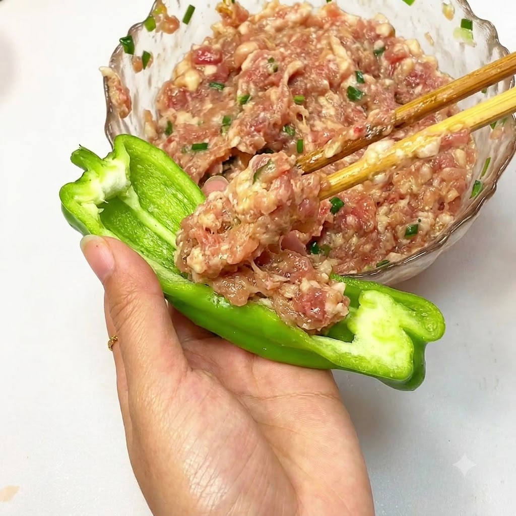 半分に切ったピーマンにひき肉の具材を詰めている様子。