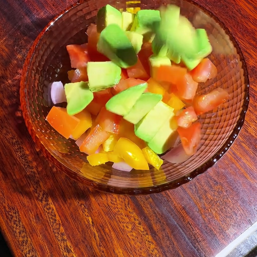 角切り野菜とアボカドの入ったボウルに、オイルとレモン汁を加えて和え、味付けをしている様子。