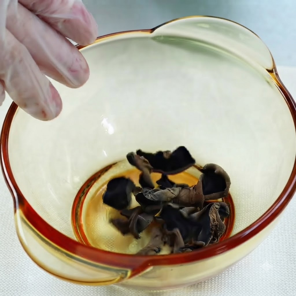計量カップから乾燥黒キクラゲを入れたボウルに水が注がれている様子。