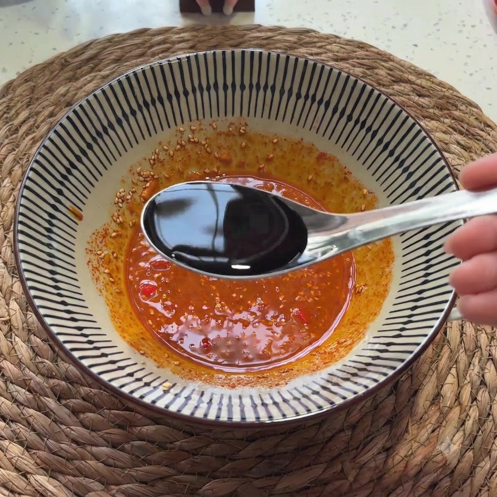 スプーンから味付け用のソースの混合物へと薄口醤油が注がれている様子。