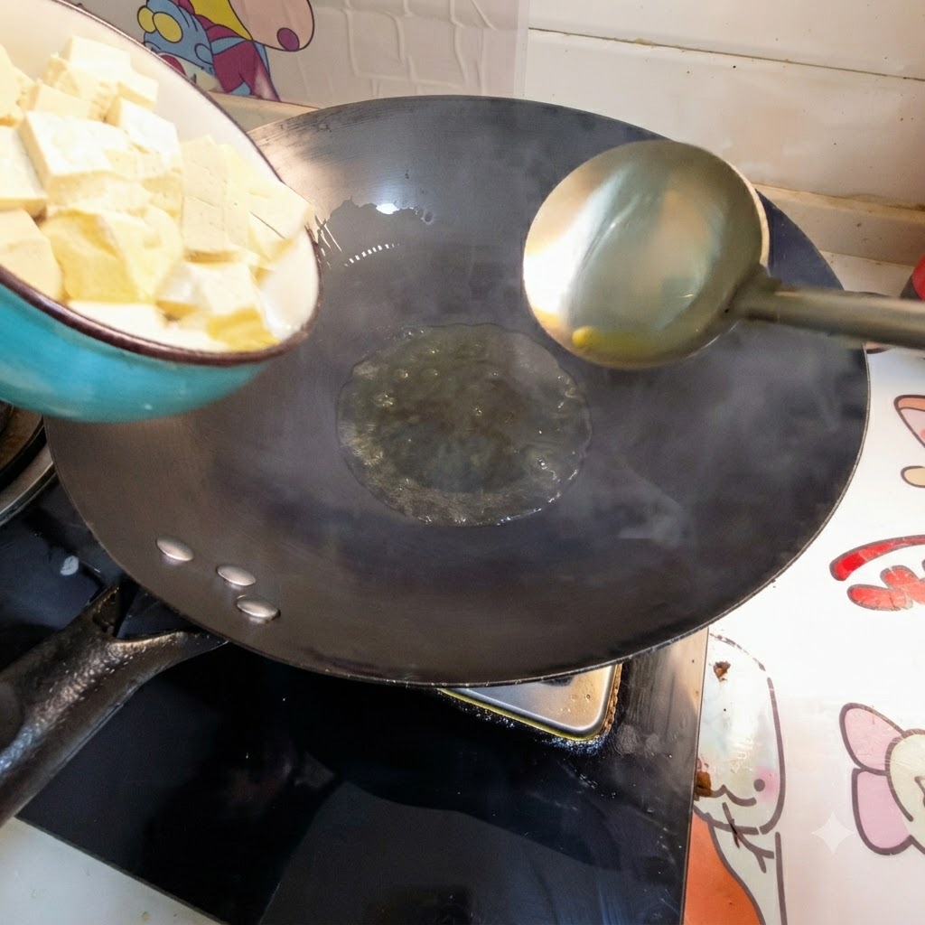 熱した中華鍋の油に角切りの豆腐をボウルから入れている様子。