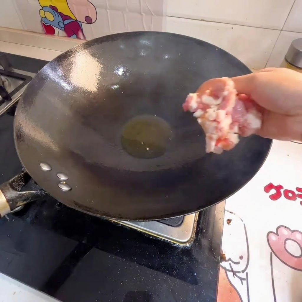 熱した中華鍋の油にひき肉を入れている様子。