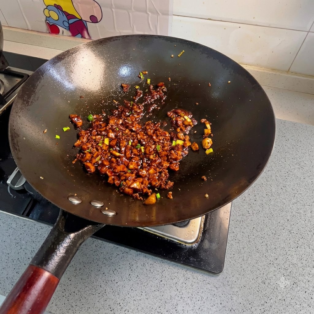 味付けしたひき肉が入った中華鍋に、角切りのにんじん、じゃがいも、炒めた豆腐を加えて混ぜ合わせている様子。