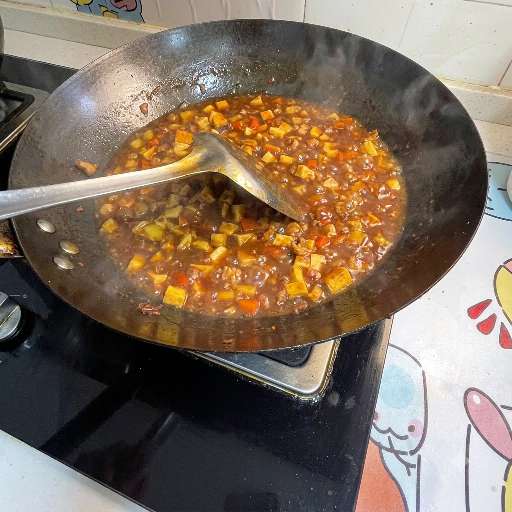 グツグツと煮立つ中華鍋のソースに水溶き片栗粉を加えてとろみをつけている様子。