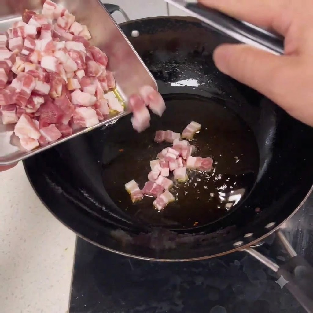 金属製のバットから、一口大の生肉を熱した油が入った中華鍋へと滑り込ませている様子。