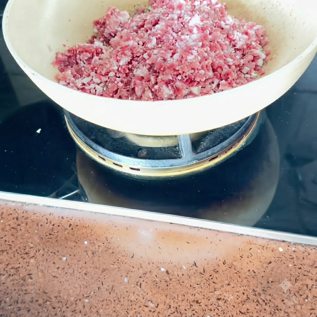 中火にかけたフライパンの中で、細かく切った豚バラ肉を炒めている様子。