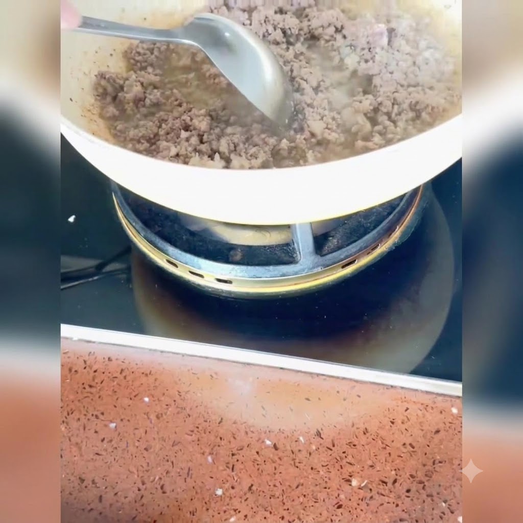 きつね色に炒まった豚肉に、みじん切りの長ねぎ、生姜、にんにくを加えて一緒に炒め合わせている様子。