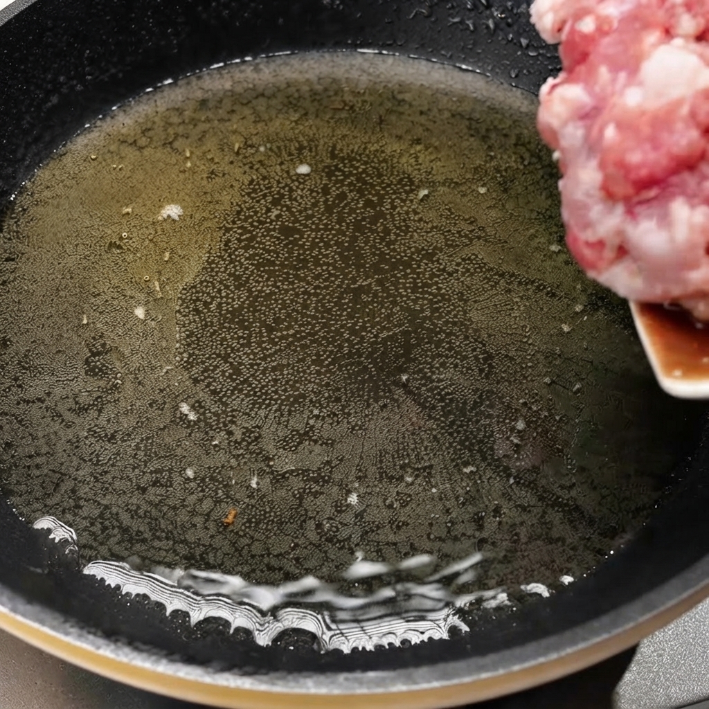 熱したフライパンに油をひき、細切り肉を入れて調理を始めている様子。