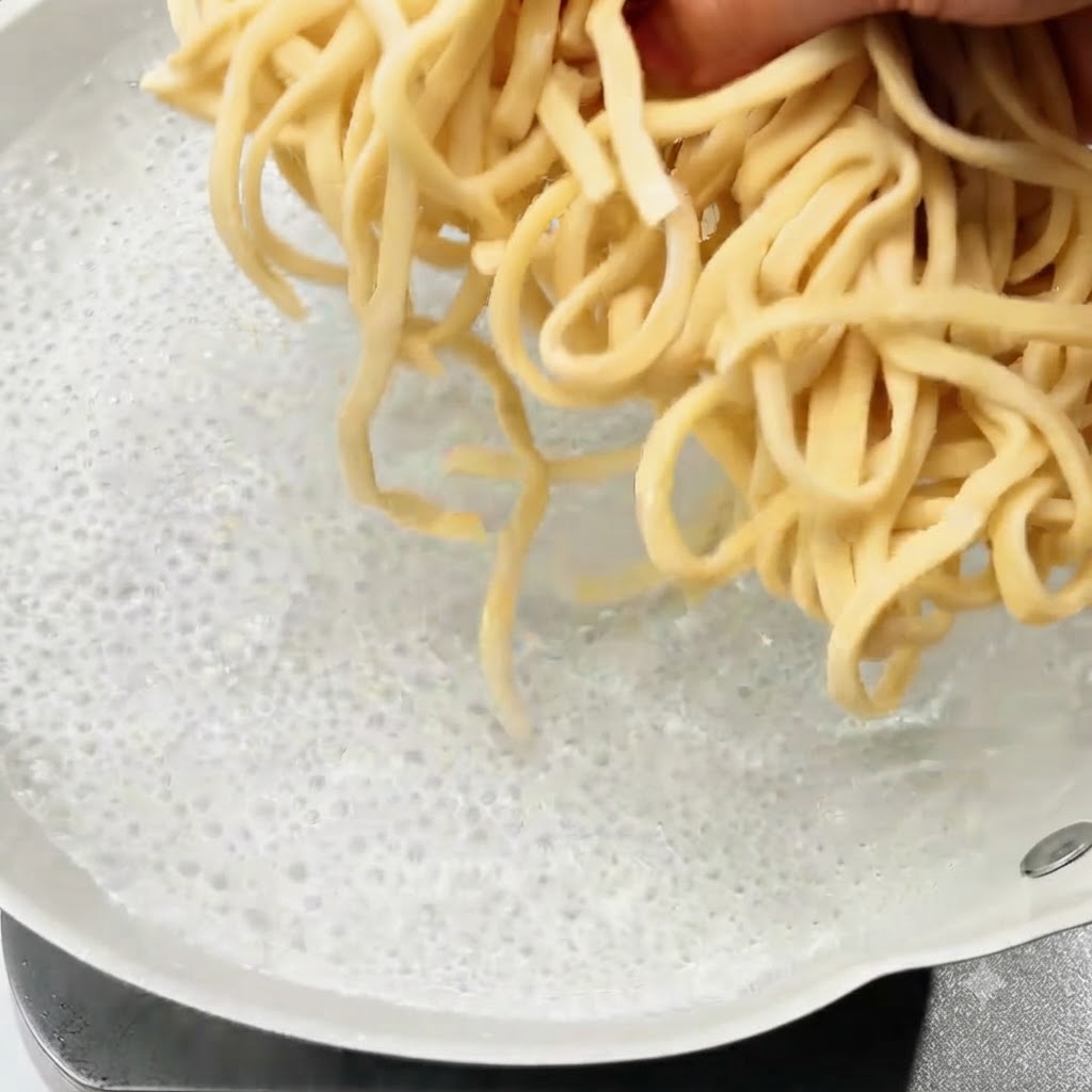 沸騰したお湯の入った鍋に、生麺を投入している様子。