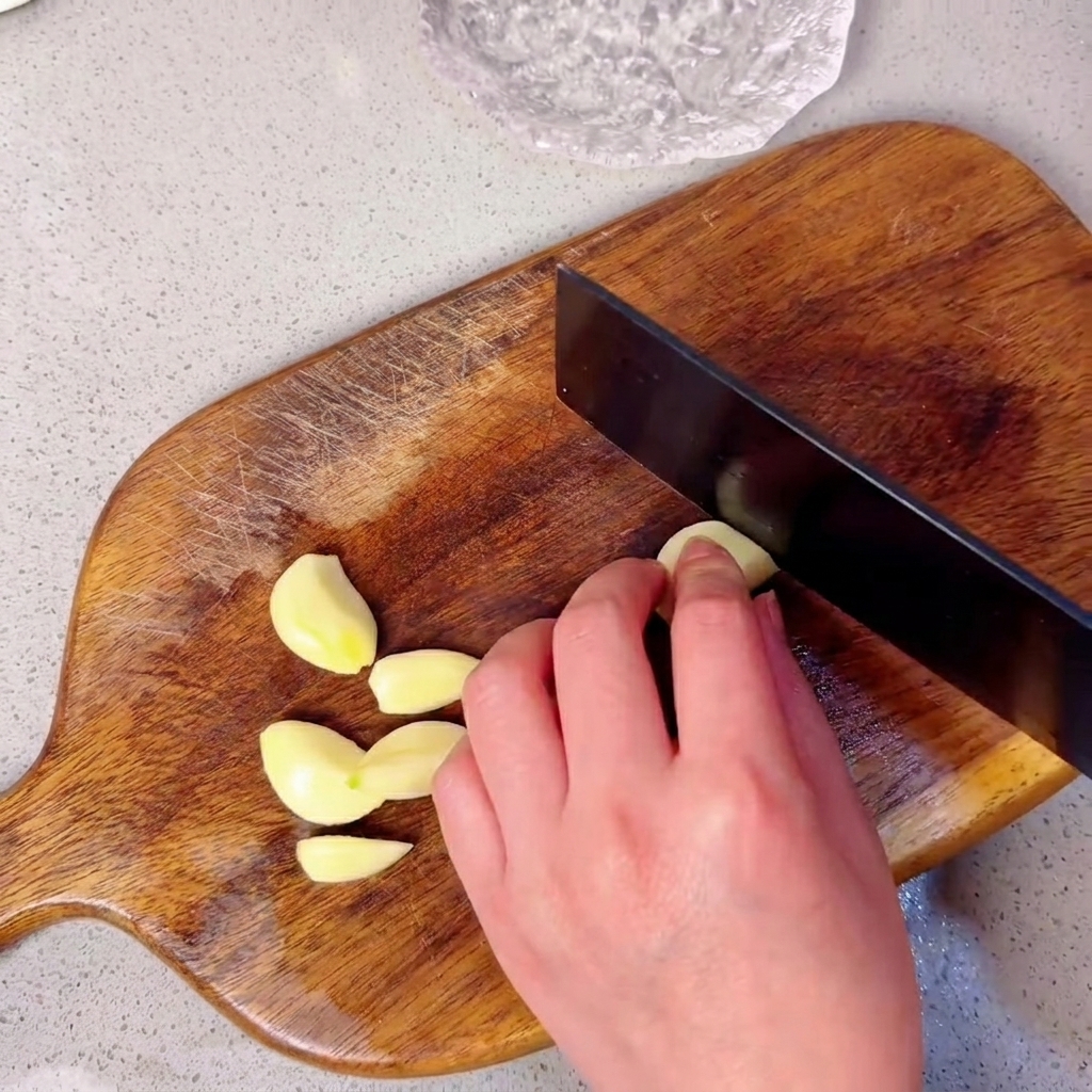 みじん切りにするために木製のまな板の上に並べられたにんにくの cloves。