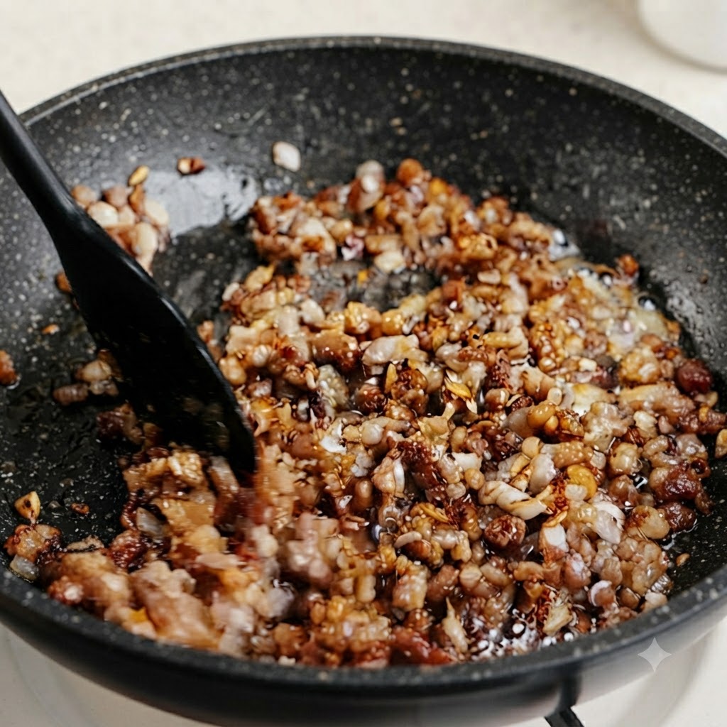 煮込んでいる味付けされたひき肉のフライパンに、刻んだ緑のニラやネギの茎を混ぜ入れている様子。