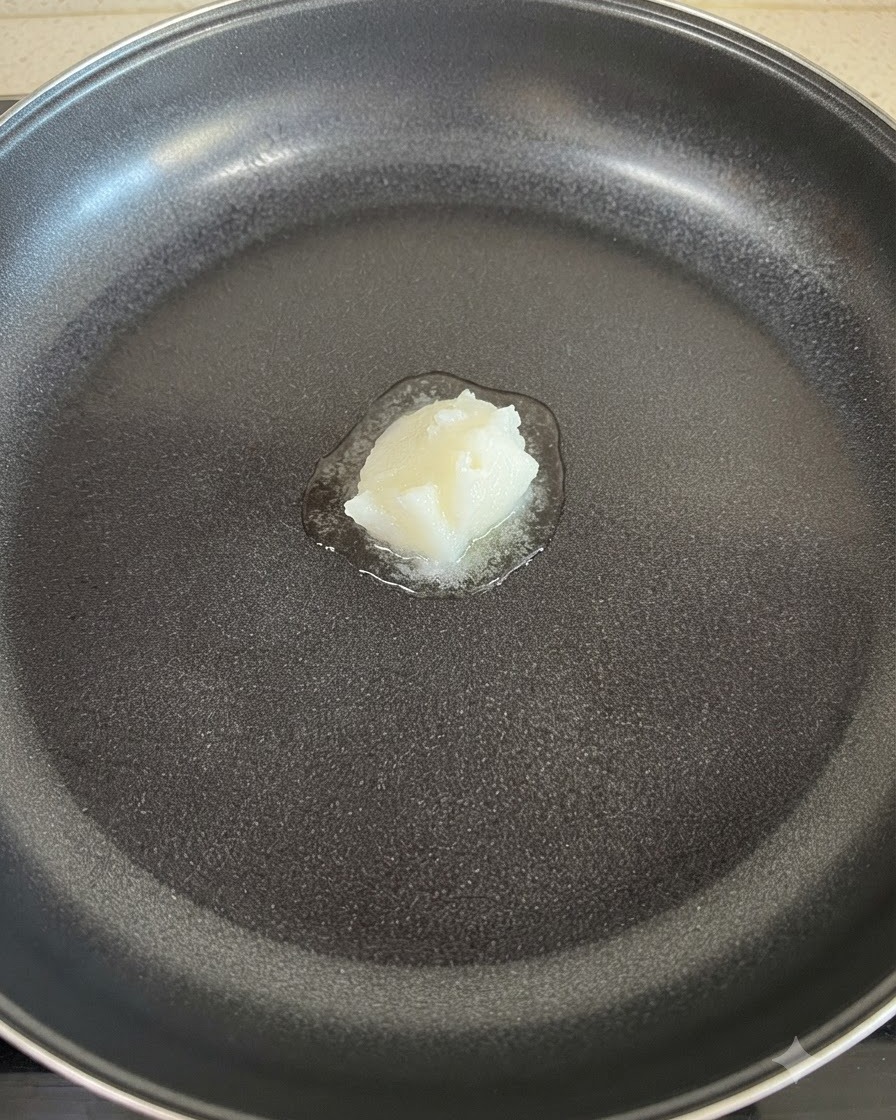 フライパンの中央で白いラードが溶けている様子