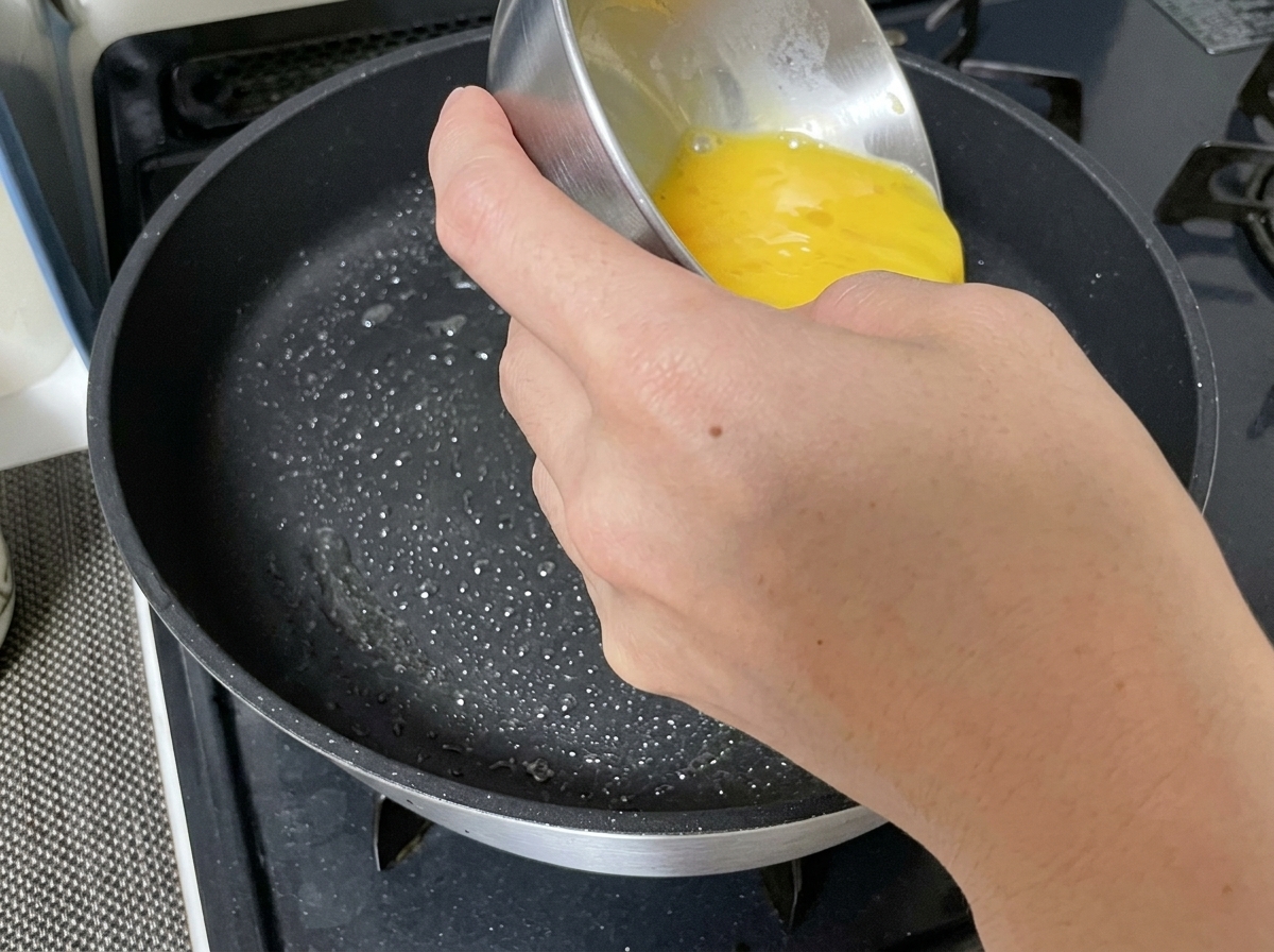 熱したフライパンに溶き卵の液が流し込まれている様子。