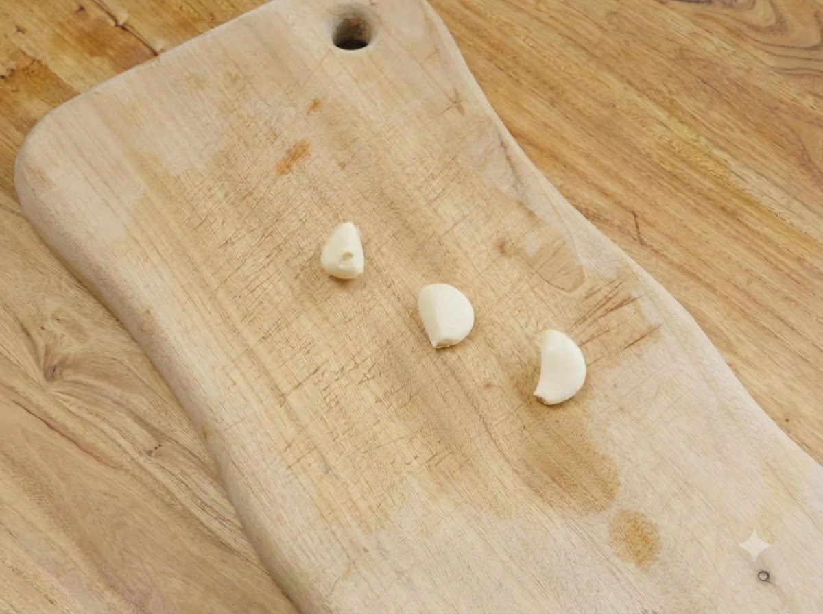 木のまな板の上に置かれた皮をむいた3片のにんにく