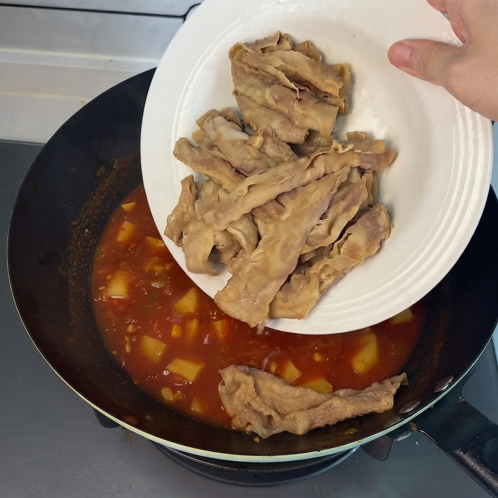 白い皿から、旨味たっぷりの赤いスープが入った中華鍋へ、あらかじめ湯通しした牛肉巻きが滑り落ちているところcite: 1