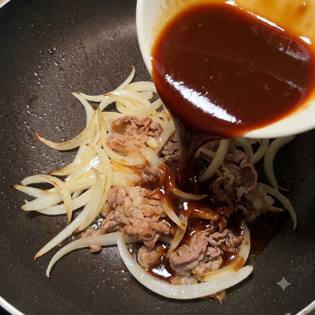 炒めた牛肉と玉ねぎの入ったフライパンに、小鉢からとろみのある照り焼きソースを注ぎ入れている様子。