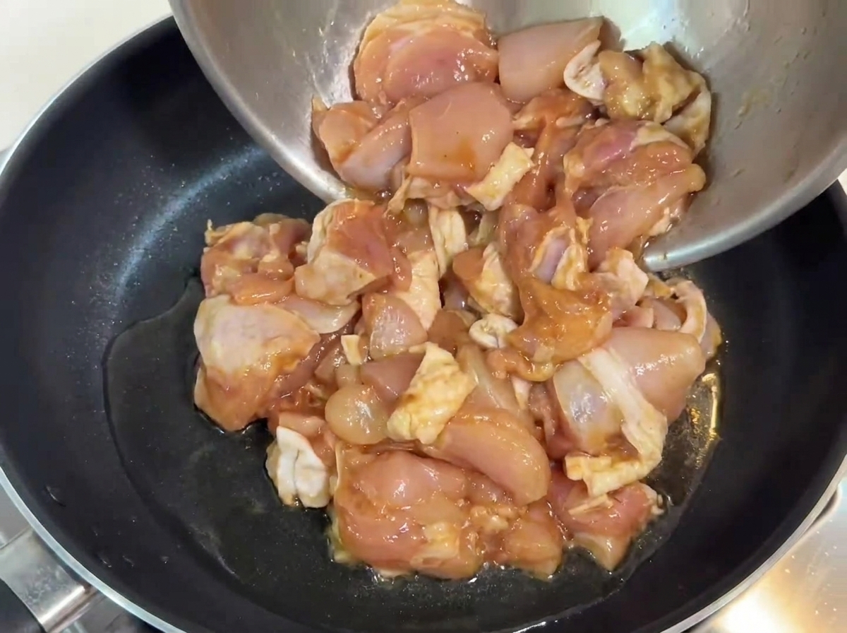 温まった油を引いたフライパンに、下味をつけた鶏肉を入れている様子。