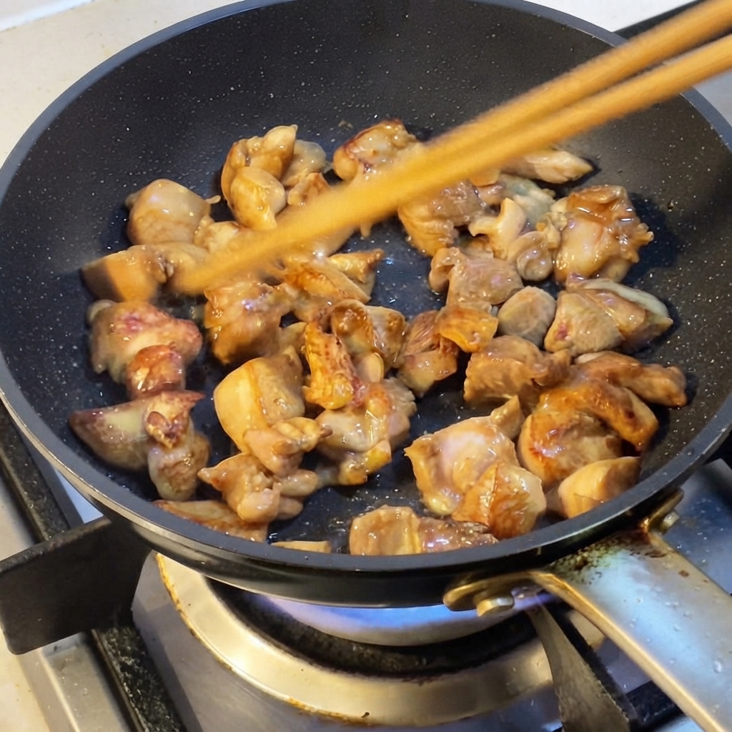 フライパンの中で菜箸を使って鶏肉を炒めている様子。