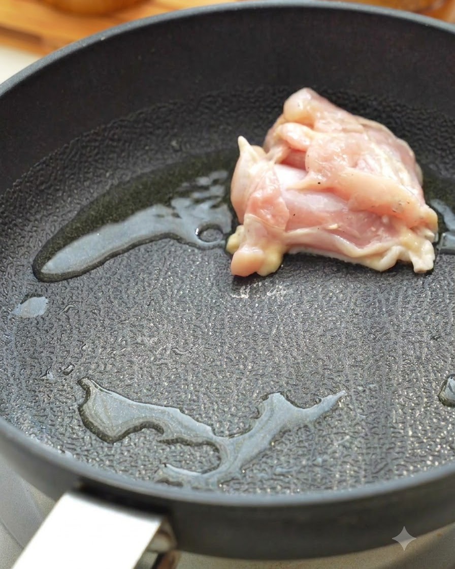 熱したフライパンで鶏肉を焼いている様子。