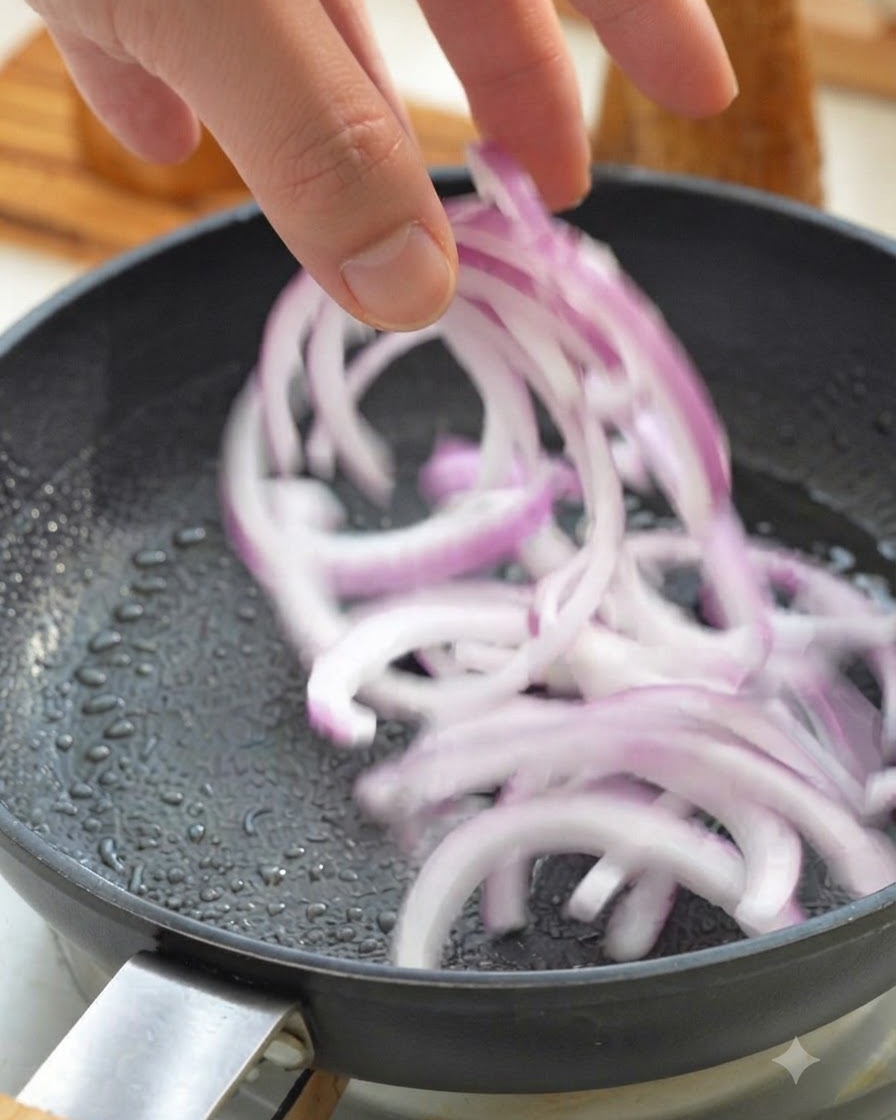 フライパンにスライスした玉ねぎを入れて炒めている様子。