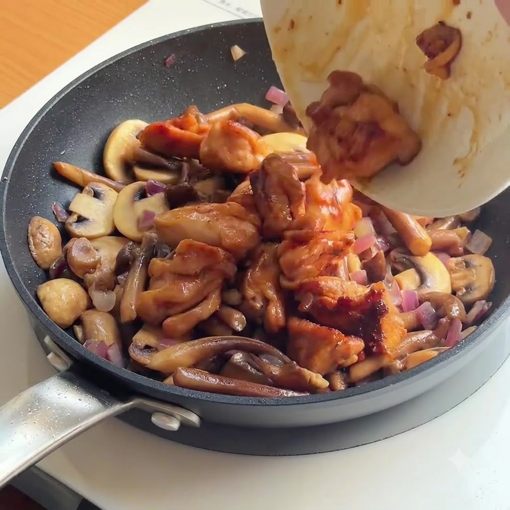 キノコと玉ねぎを炒めたフライパンに焼いた鶏肉とご飯を投入する様子。