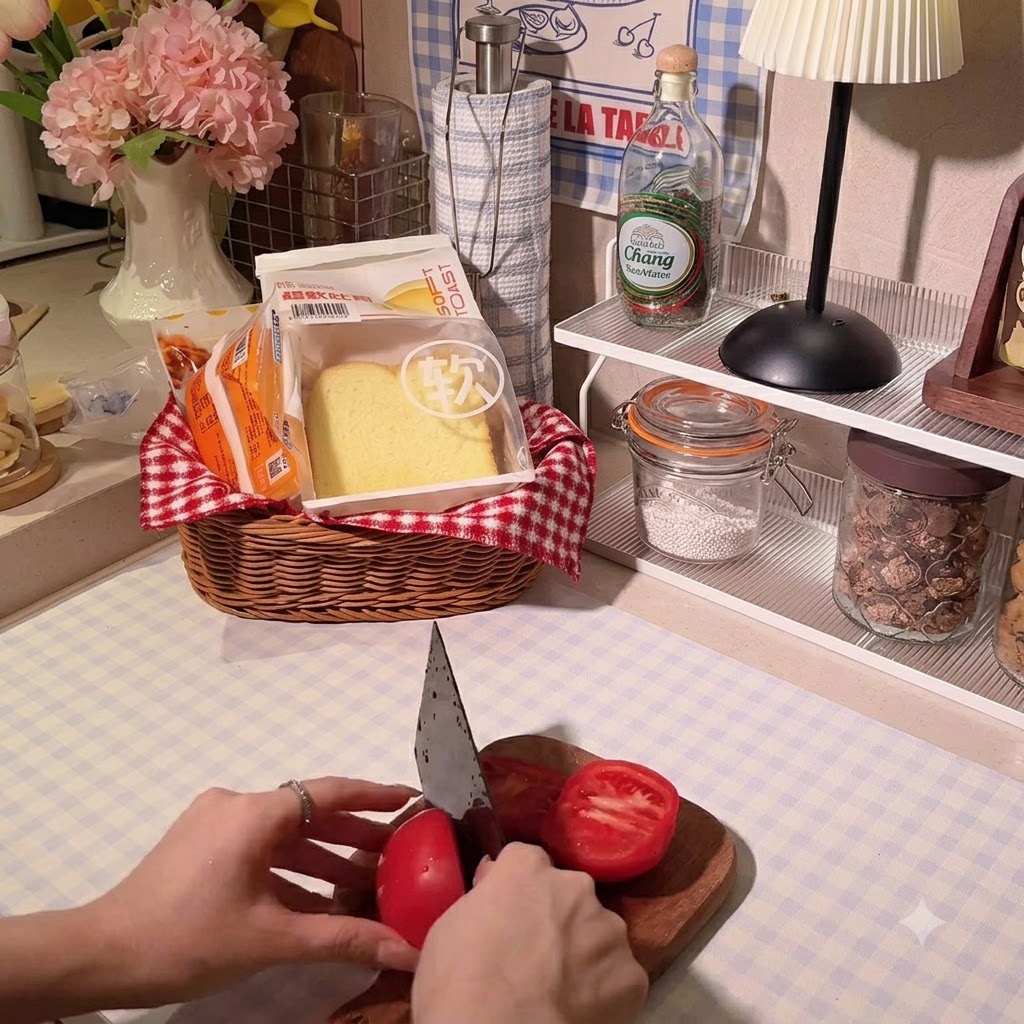 木製のまな板の上で、シェフナイフを使って真っ赤なトマトをスライスしている手。