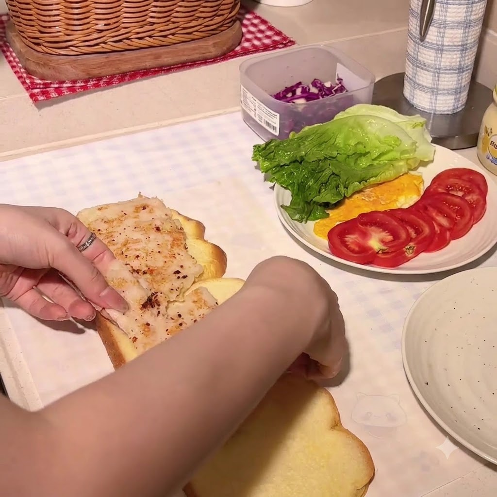 チキンカツを重ねたパンプキンブレッドの slices にハニーマスタードを絞りかけている様子。