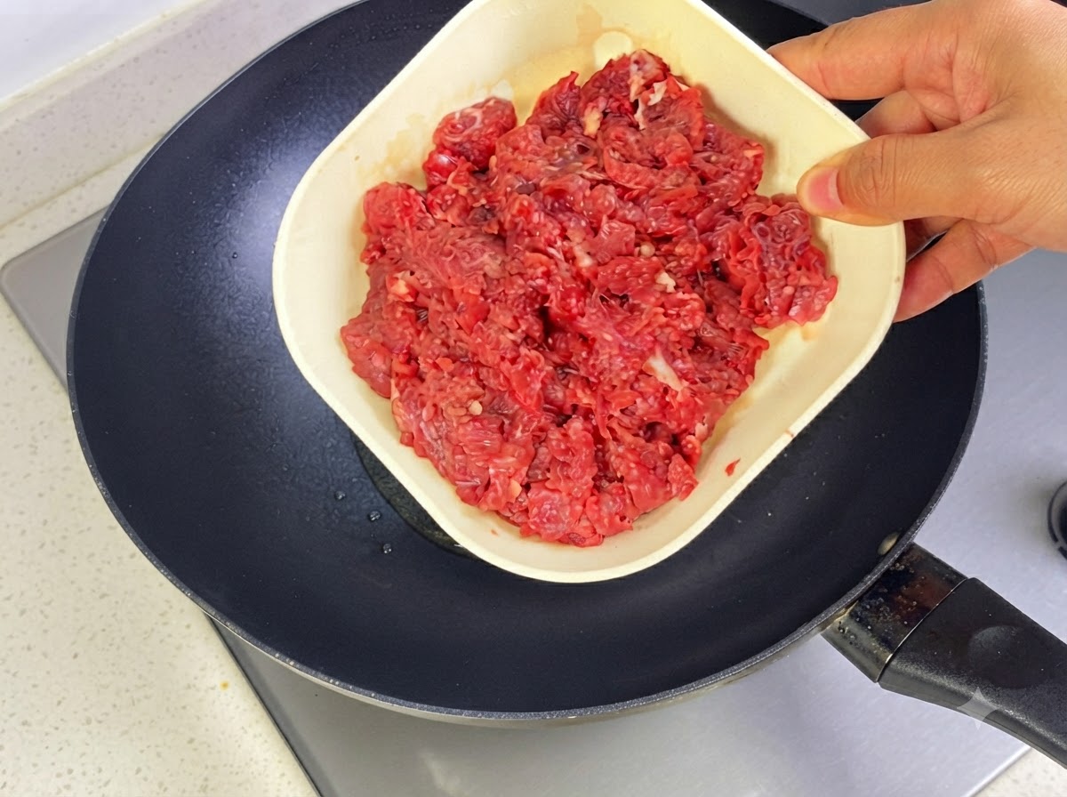 熱したフライパンの油の中で、牛ひき肉を炒めている様子。
