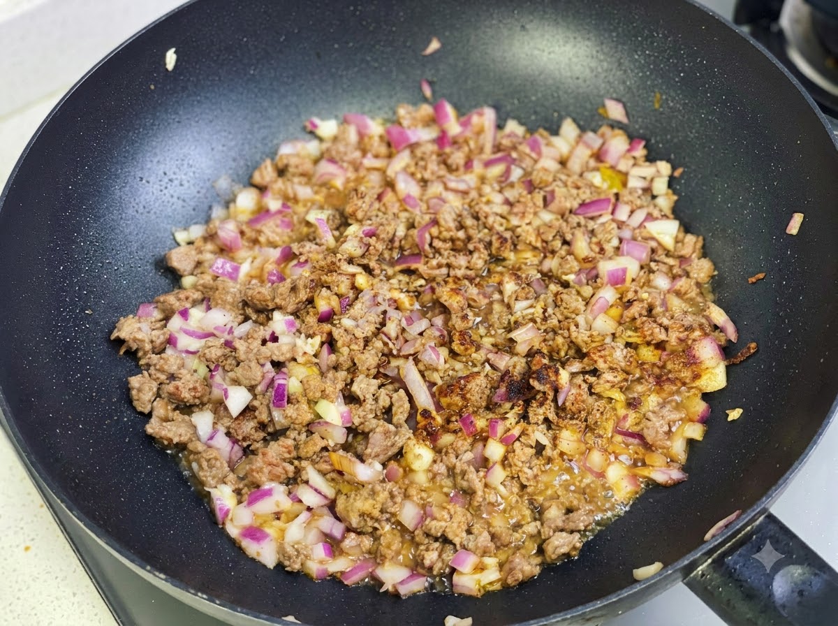 牛肉と玉ねぎのミックスに、カレールーとスパイスを加えて炒めている様子。