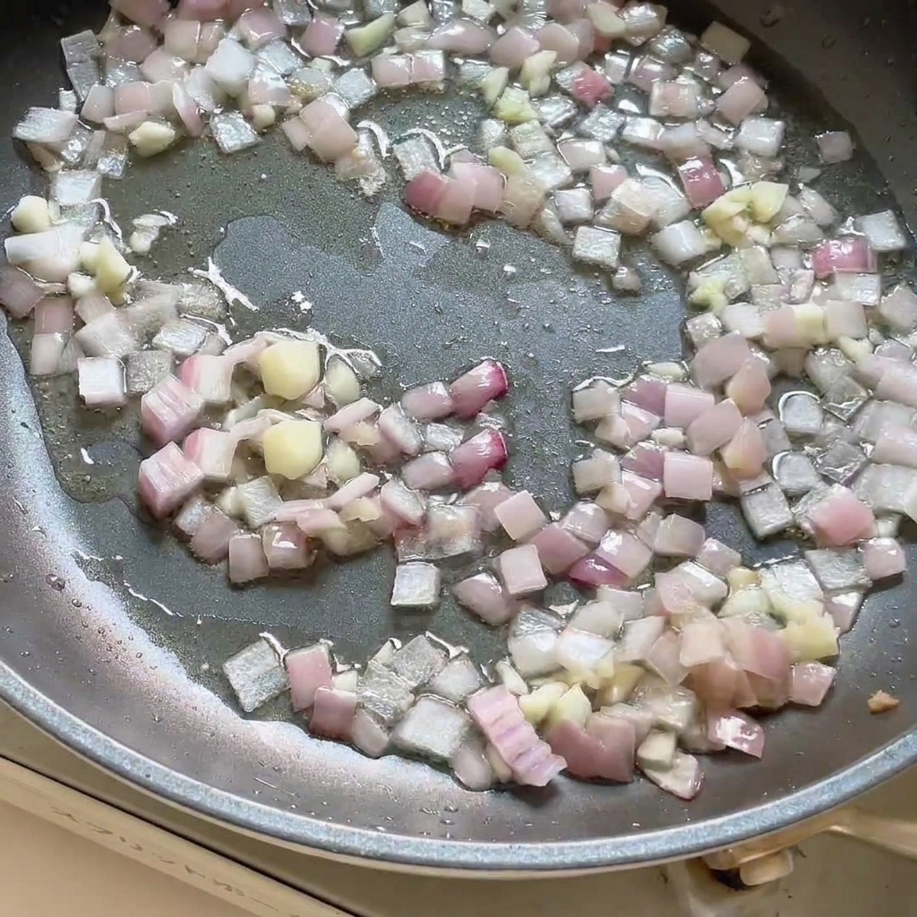 炒めた玉ねぎとにんにくの入ったフライパンにカレーペーストを加え、混ぜ合わせている様子。cite: 1