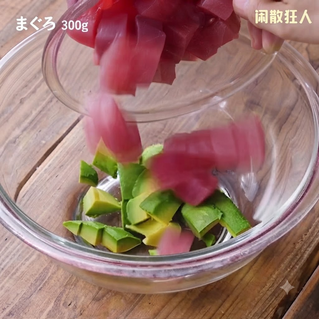 小さなボウルから、アボカドの入ったガラスのボウルへ、新鮮な角切りマグロを入れているところ。