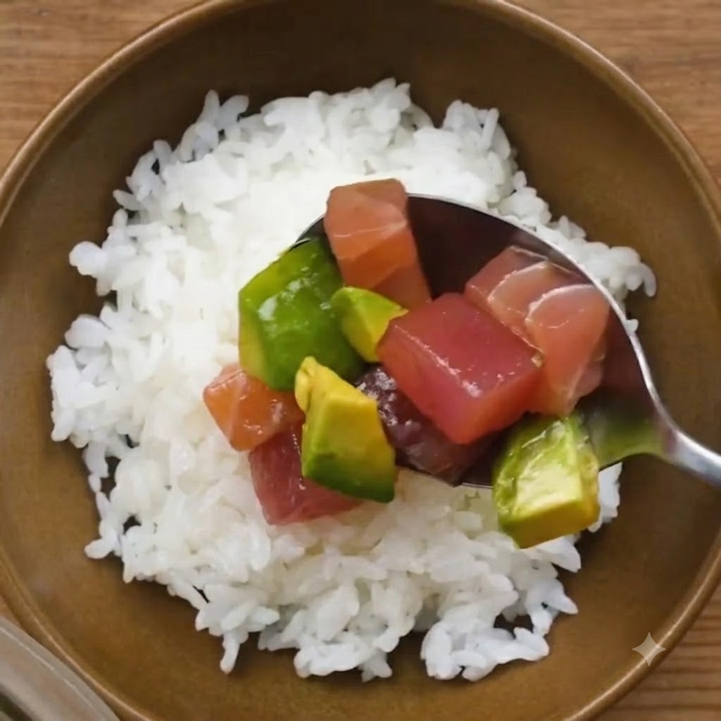 白すし飯を入れた丼ぶりに、スプーンですくった漬けマグロとアボカドをのせているところ。