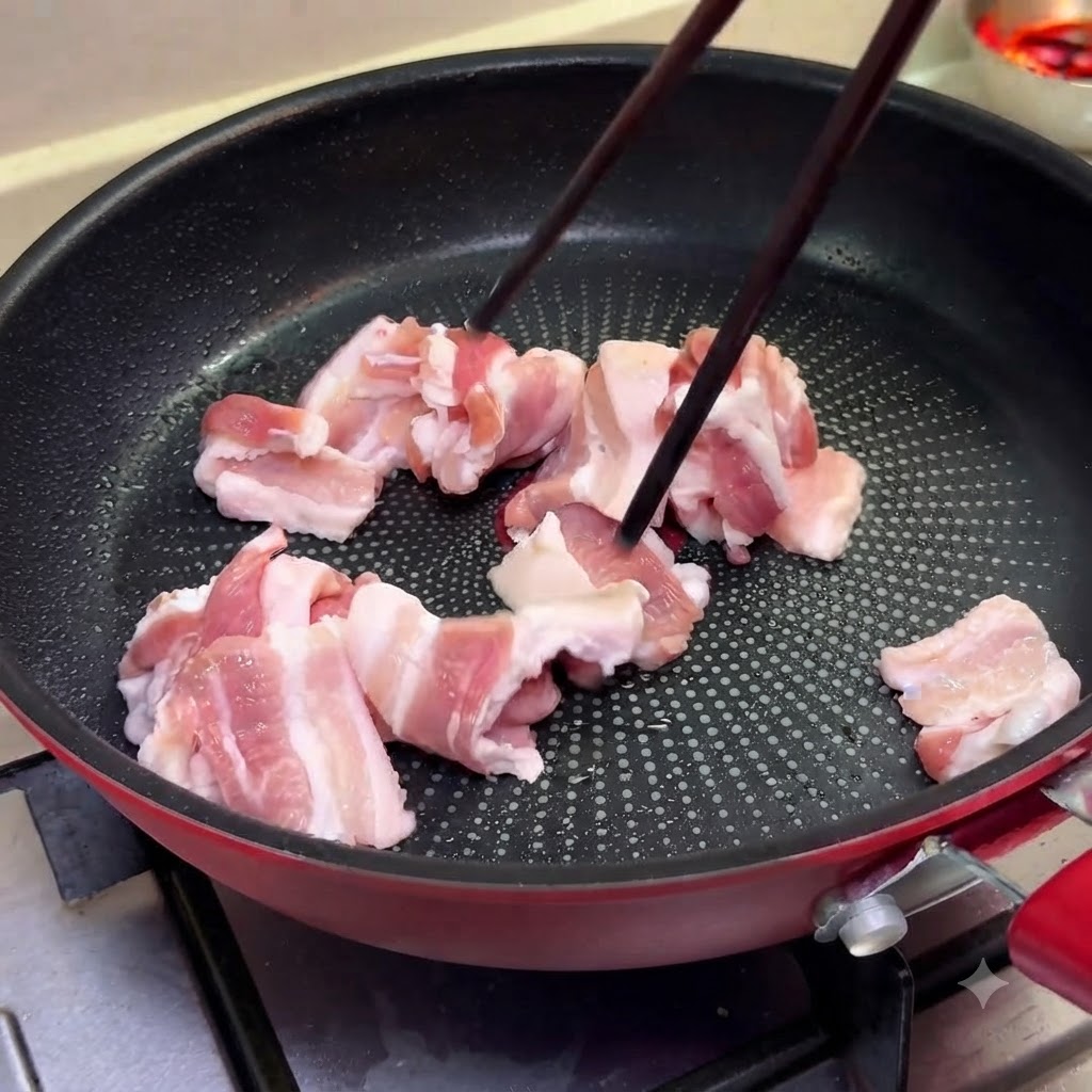 フライパンで豚バラ肉を中火で焼き、菜箸で裏返している様子。