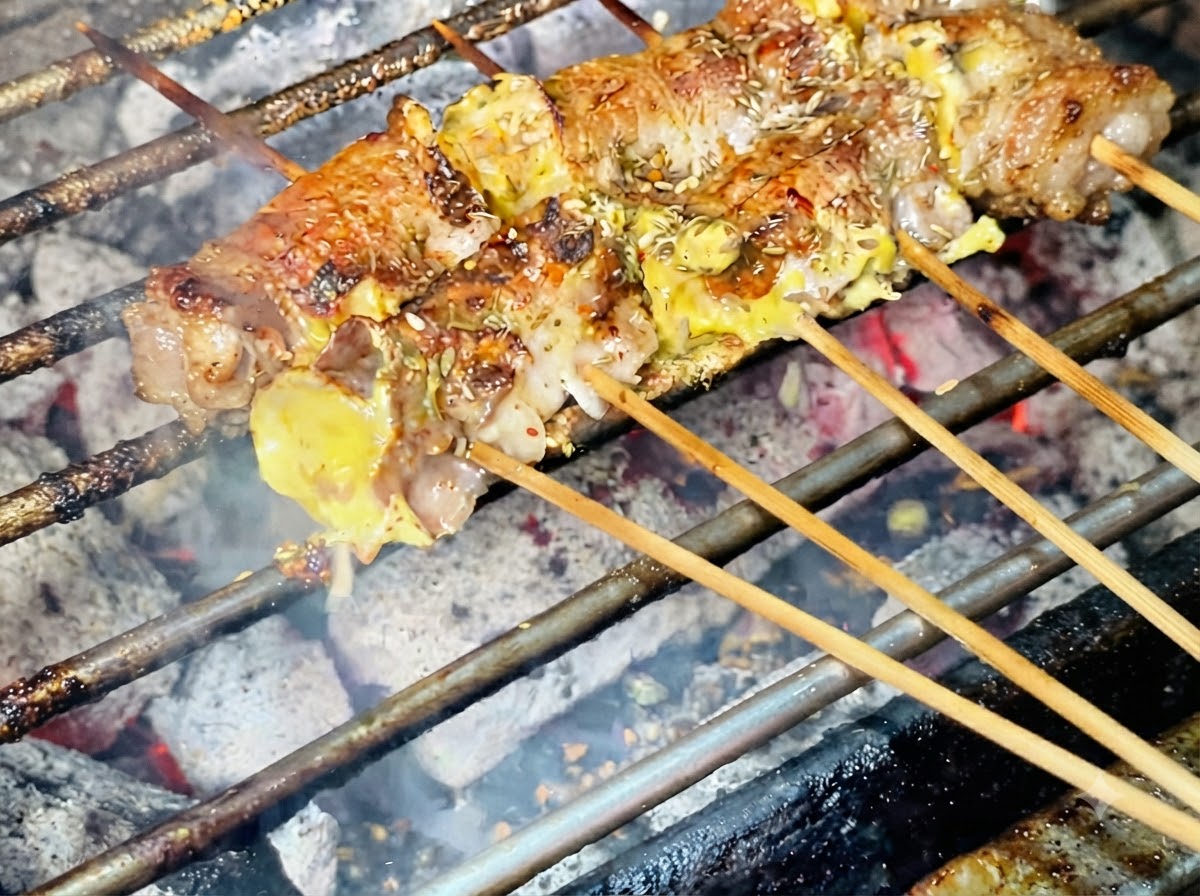 焼き上がりに近づいた肉巻きの上に、ごまが振りかけられている様子。