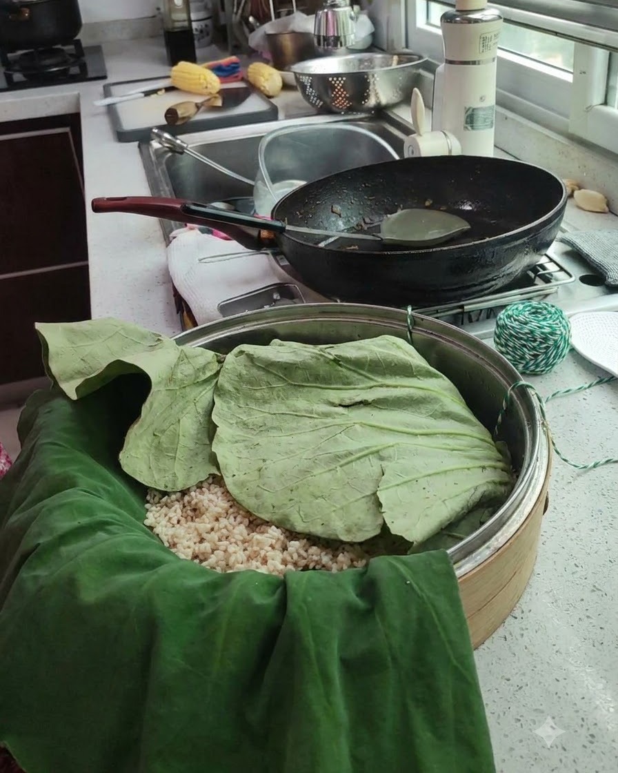 蓮の葉で包んだパッケージが蒸し器に置かれ、緑と白の調理用タコ糸が近くに添えられている様子。