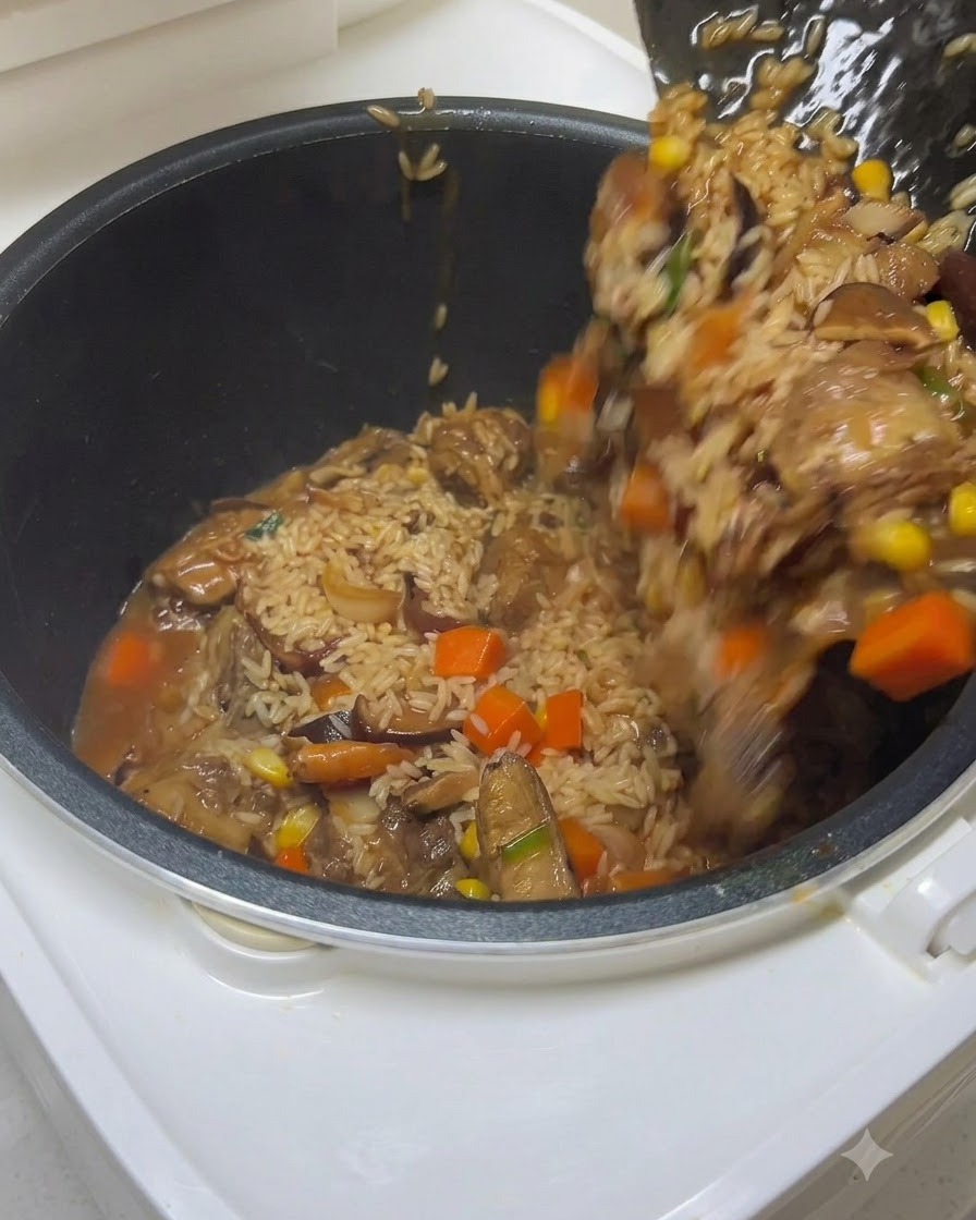 ヘラを使って、味付けしたご飯、スペアリブ、野菜を炊飯器の釜に移しながら、水が注がれている様子。
