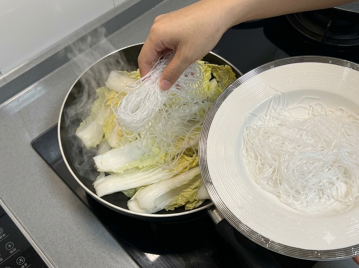 フライパンの白菜の上に、春雨を均一に配置している様子。