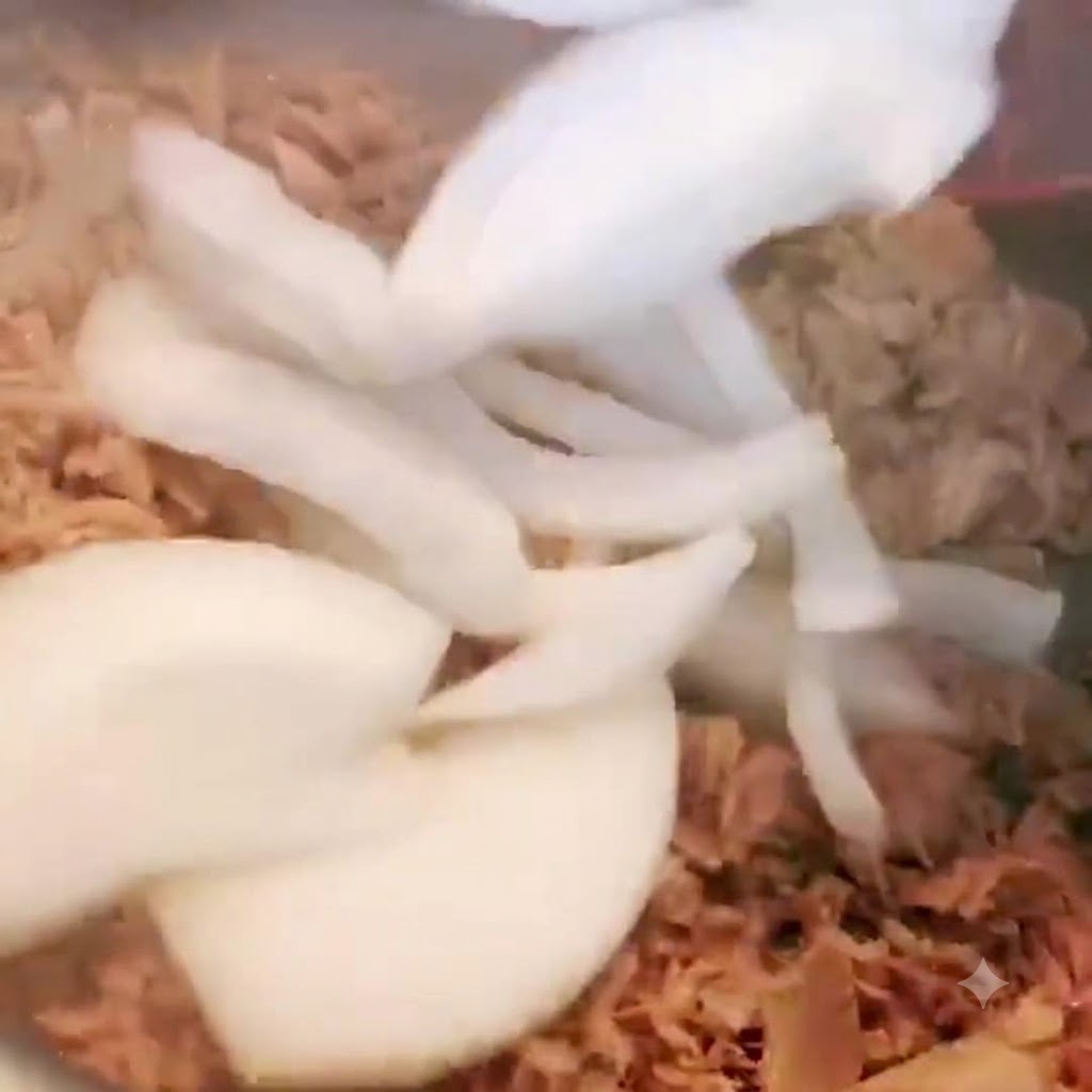 ツナの入った鍋にスライスした玉ねぎを加えて混ぜ合わせている様子。