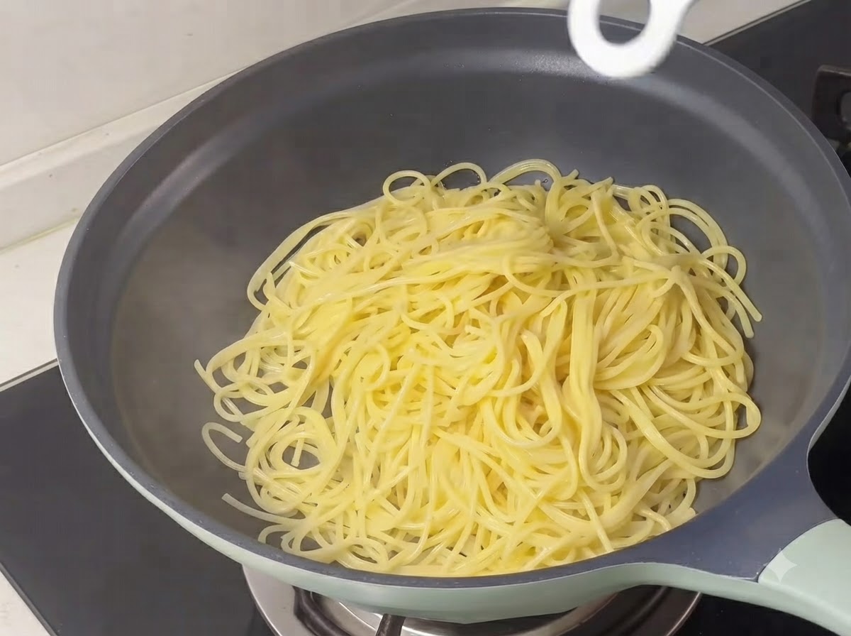 スキレットの中に、茹で上がった黄色のスパゲティの麺が山盛りにされている様子。