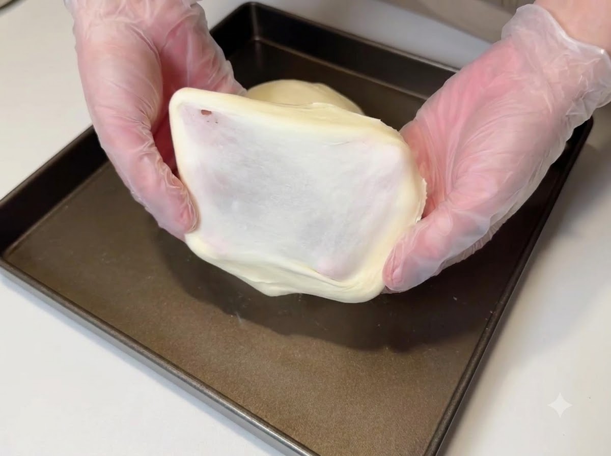 厚くなめらかな膜を見せるために伸ばされている生地の断片。