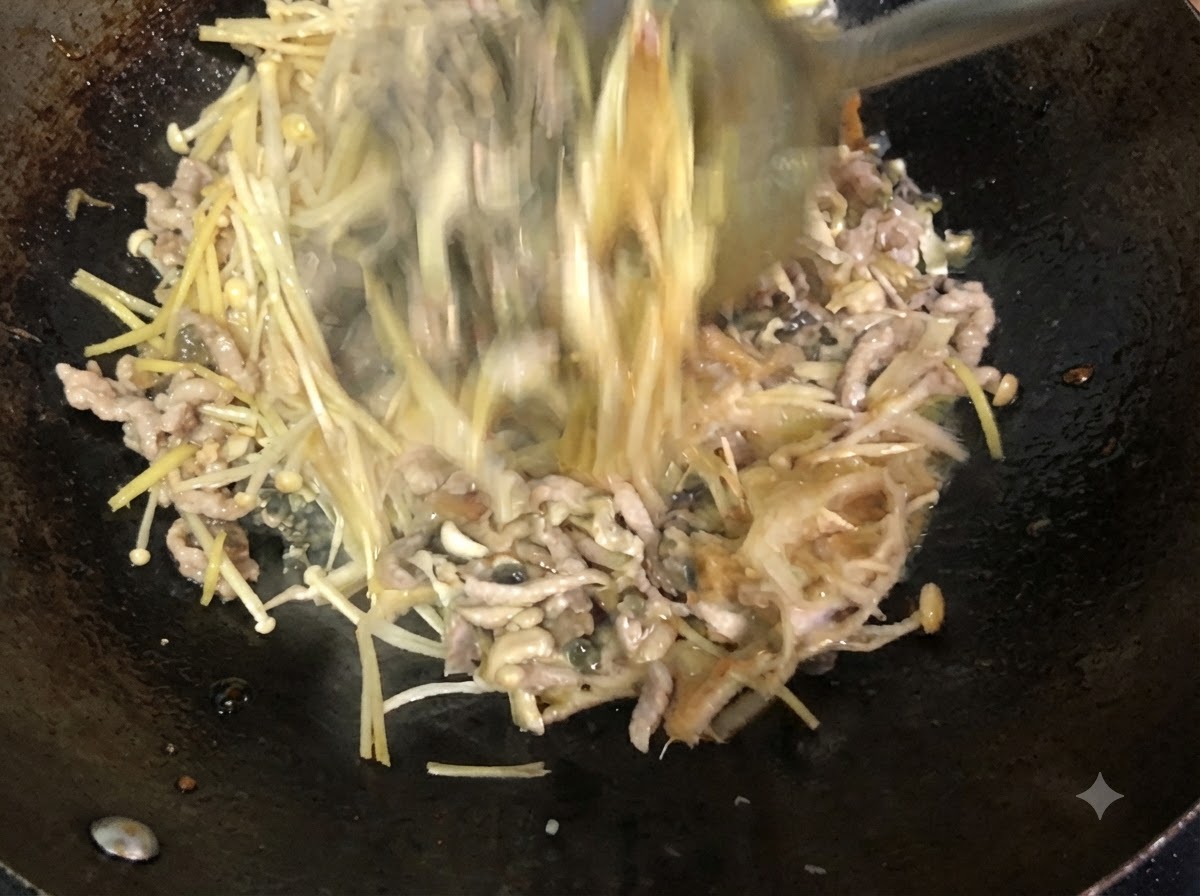 金属製のヘラを使って、中華鍋の中で具材が活発にかき混ぜられ、合わせられている様子。