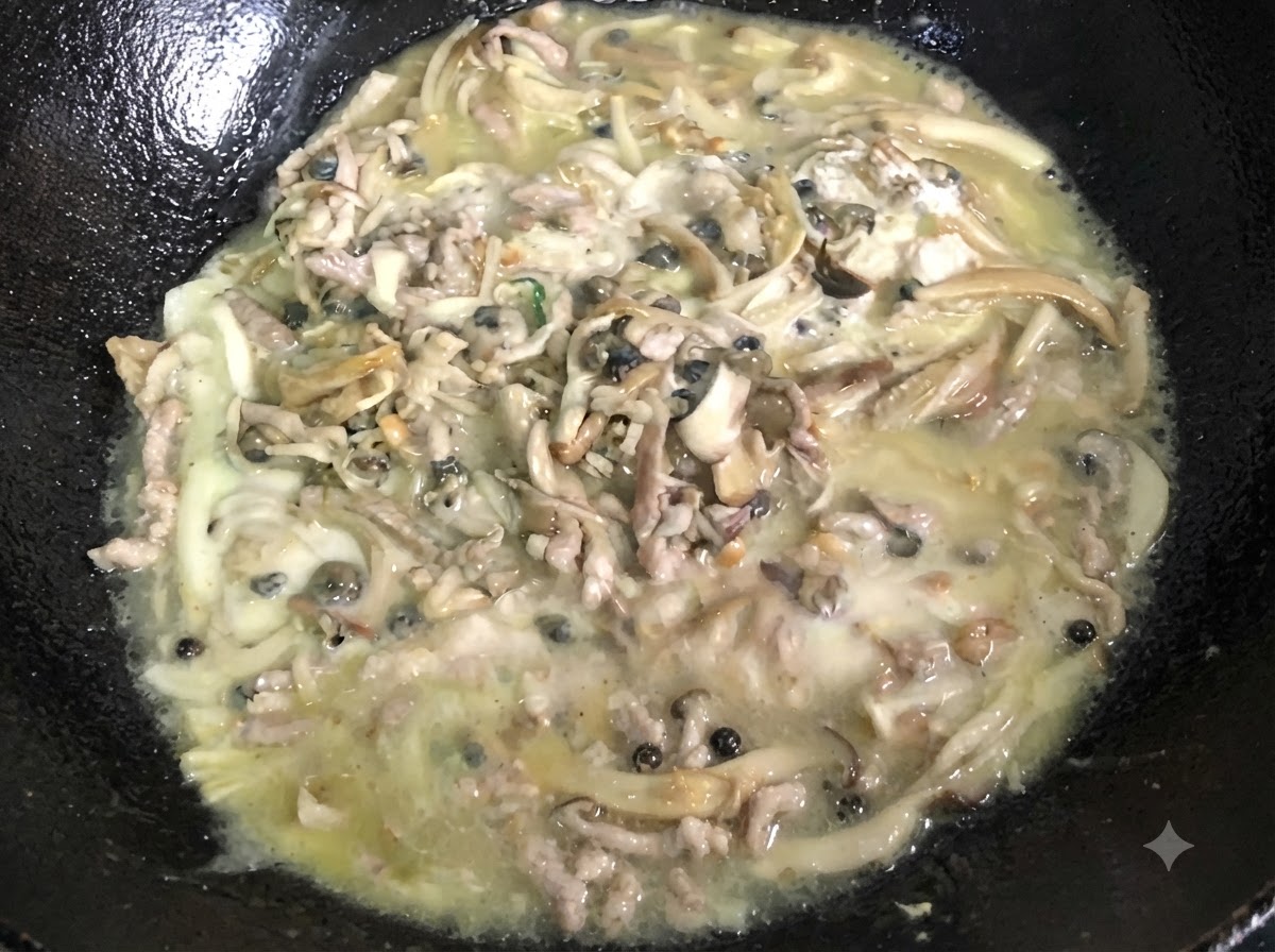 黒い中華鍋の中で、とろみのついた泡立つ混合物が絶えずかき混ぜられている様子。