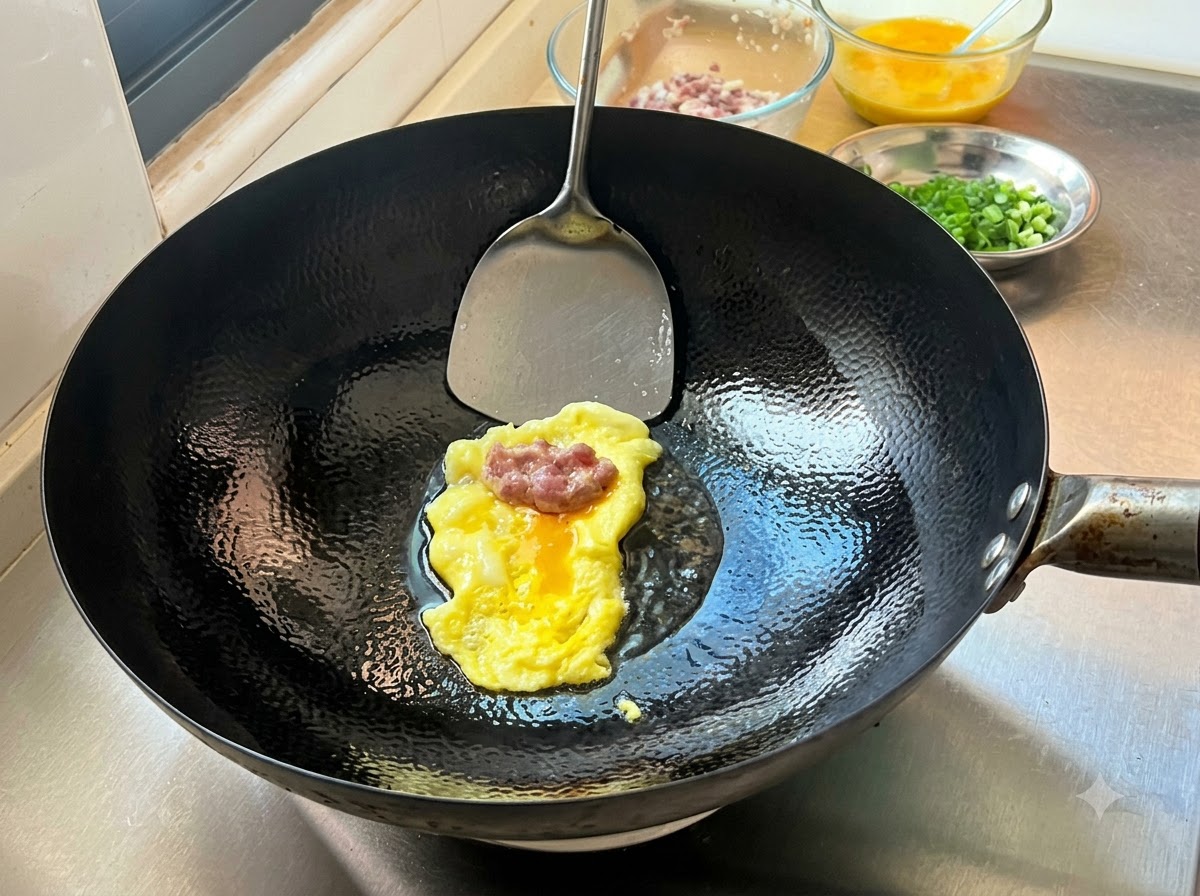 折りたたむ準備として、熱い中華鍋の中の焼き立ての薄い卵クレープの上に置かれた味付け肉の餡。