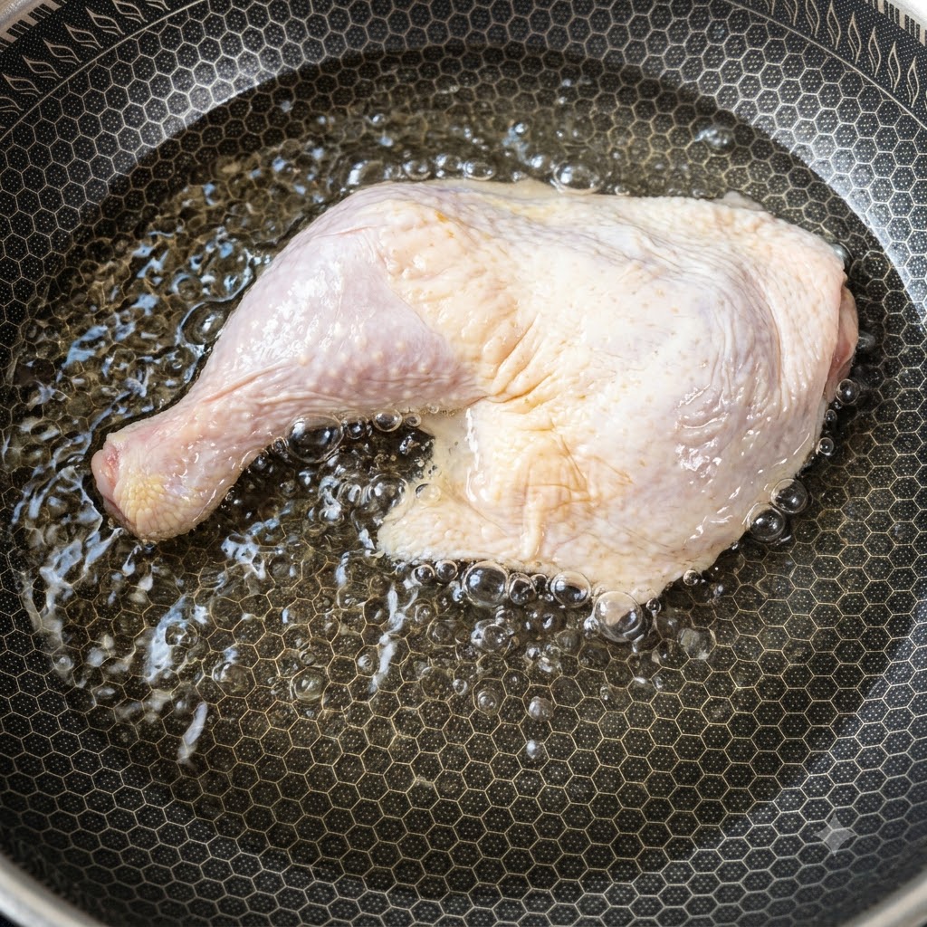 冷たい水が入った鍋に入れられ、加熱が始まった大きな生の鶏もも肉。