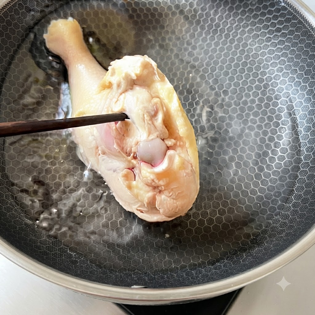 下茹でして洗った鶏もも肉を、調理鍋の冷たい水に戻し入れる様子。