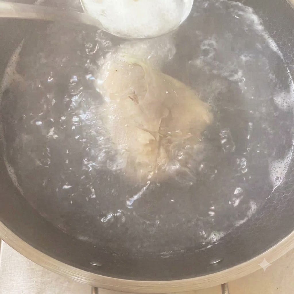 鶏肉と香味野菜が入った沸騰した鍋に、スプーン一杯の調味料を加えている様子。