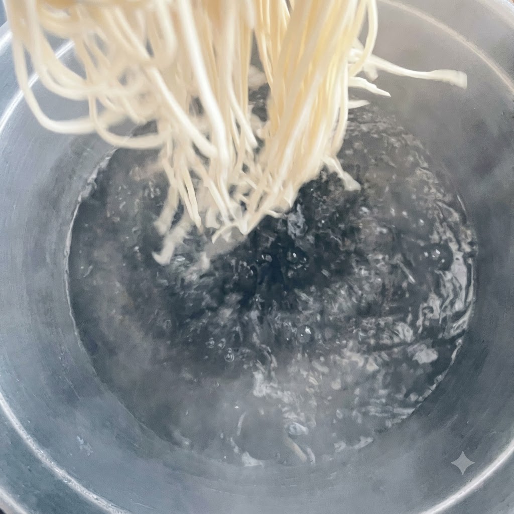 沸騰した大きなお湯の鍋に麺を投入している様子。