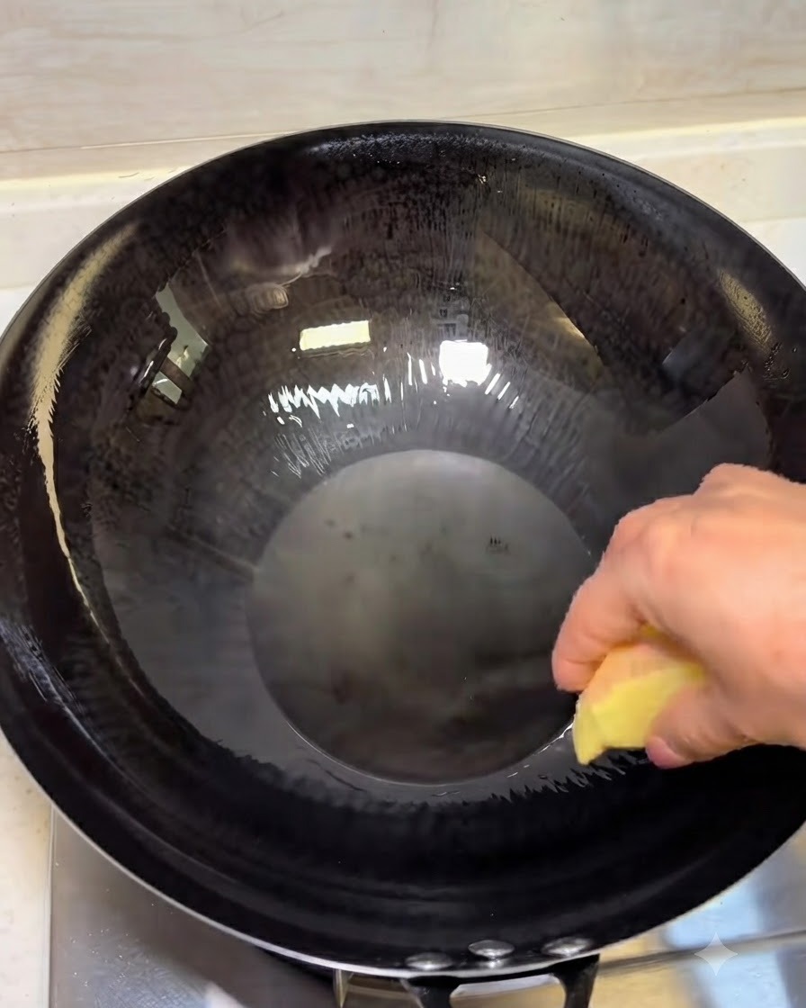 熱した油を入れた黒い中華鍋の中で、生姜のスライスが炒められている様子。