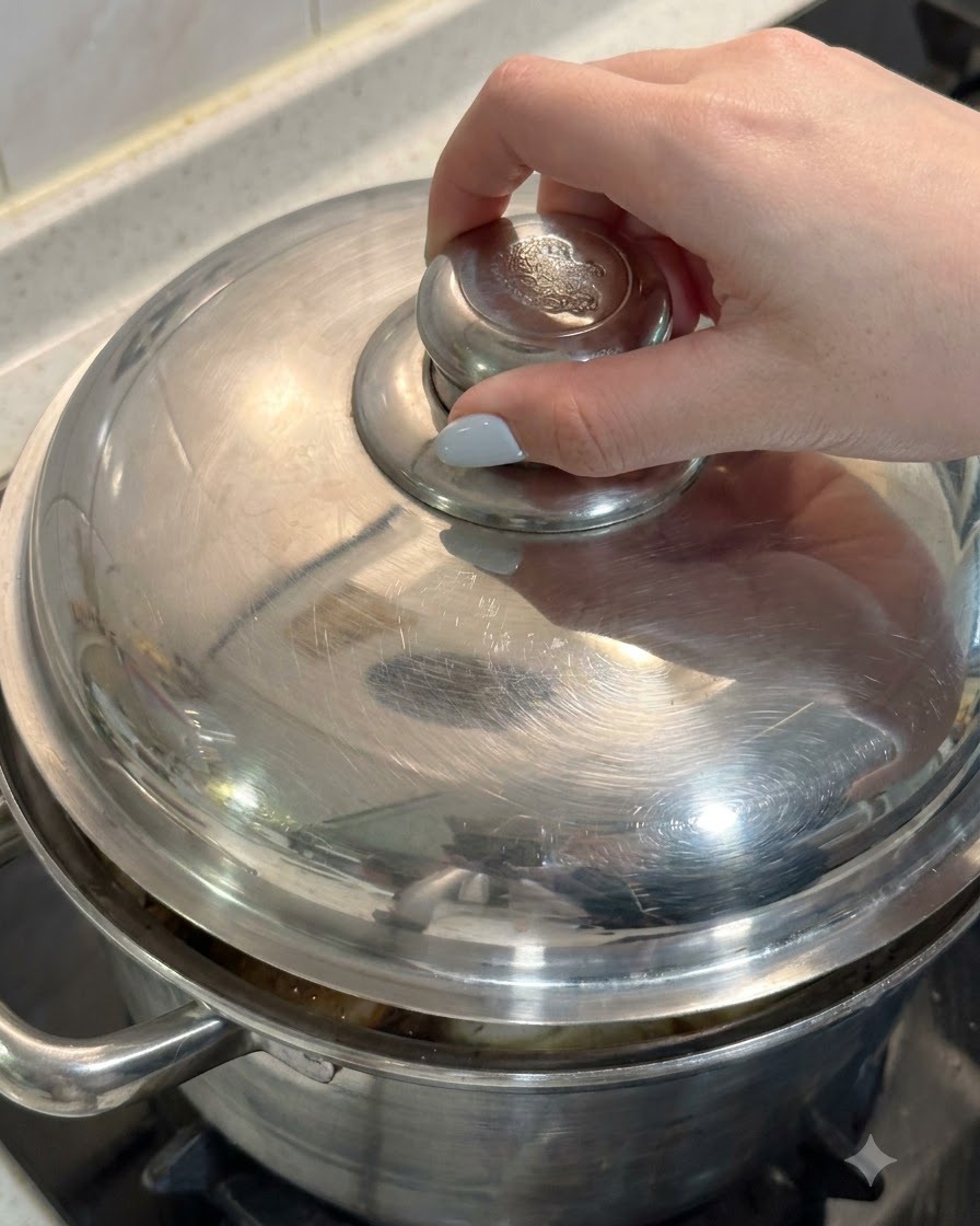 鶏肉と具材の入った鍋に、手で金属製の蓋をかぶせている様子。